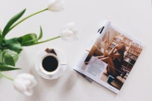 magazine and coffee on table next to white tulips